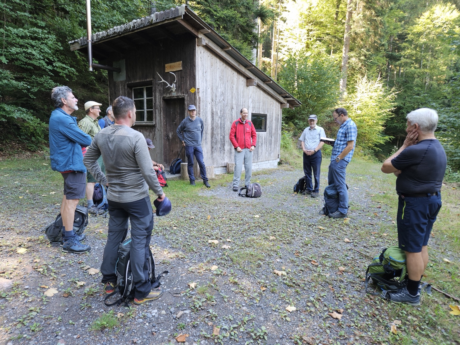 Männergruppe bei einem Impuls vor einer Waldhütte